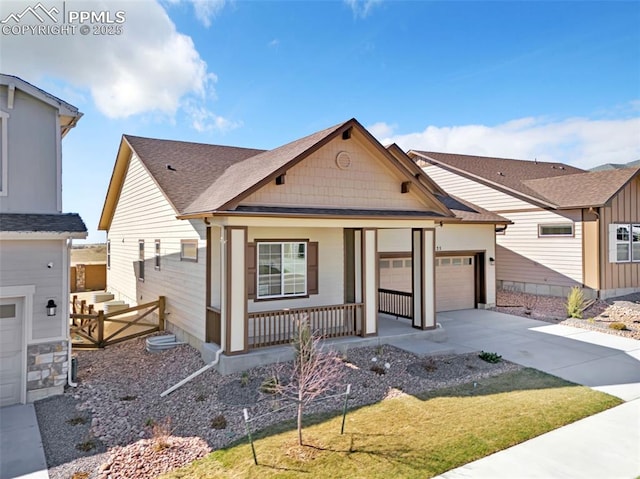 view of front of home featuring concrete driveway, a porch, a garage, roof with shingles, and fence