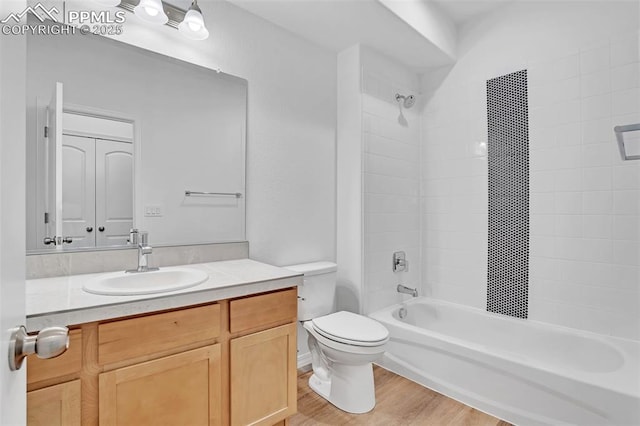 bathroom featuring toilet, shower / tub combination, wood finished floors, and vanity