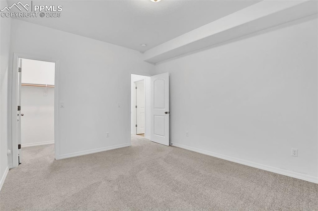 unfurnished bedroom with carpet floors, a spacious closet, and baseboards