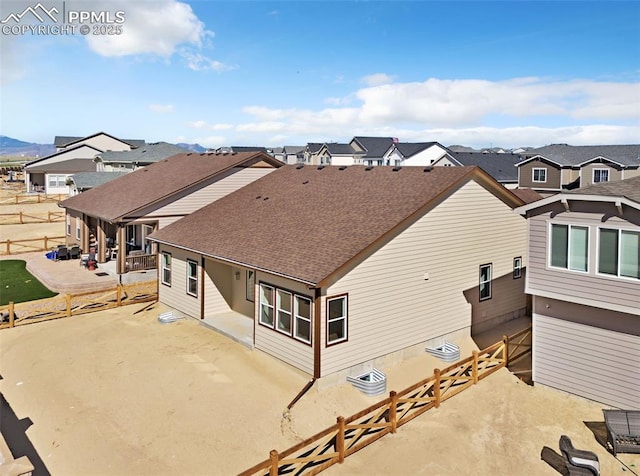 rear view of house featuring a patio, a fenced backyard, roof with shingles, and a residential view