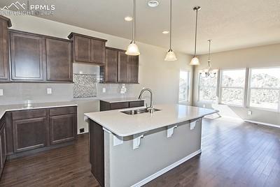 kitchen featuring sink, decorative light fixtures, dark brown cabinetry, decorative backsplash, and dark hardwood / wood-style floors