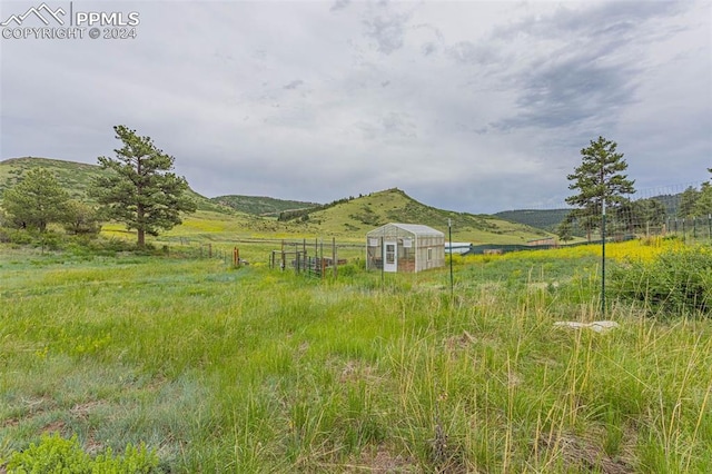 view of yard featuring a mountain view, an outdoor structure, and a rural view