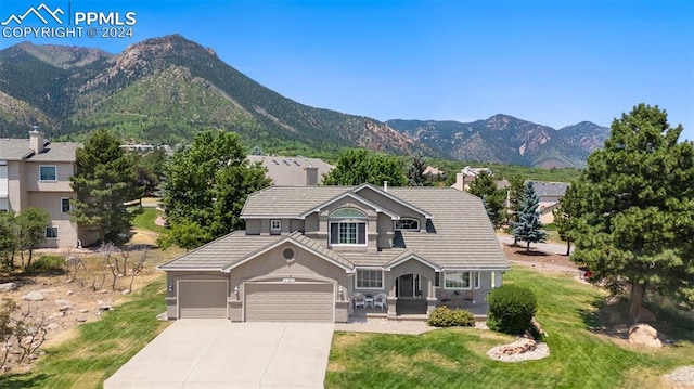 view of front of home with a mountain view, a garage, and a front lawn