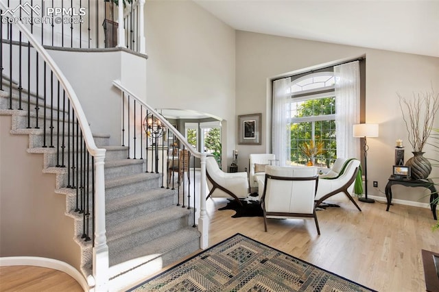 stairway featuring hardwood / wood-style floors and high vaulted ceiling