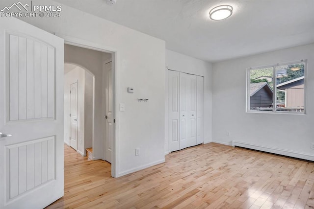 unfurnished bedroom featuring baseboard heating and light wood-type flooring