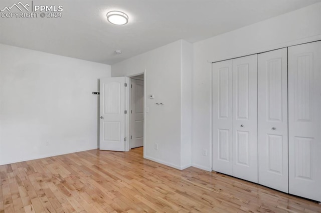 unfurnished bedroom with a closet and light hardwood / wood-style floors