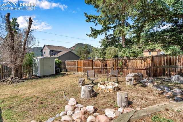 view of yard with a storage shed, a mountain view, and a fire pit