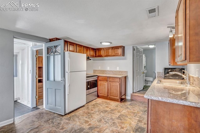 kitchen featuring sink, stainless steel electric range oven, and white fridge