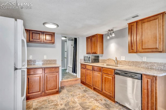 kitchen with light stone counters, sink, a textured ceiling, and appliances with stainless steel finishes