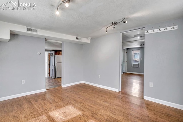 spare room with light wood-type flooring and a textured ceiling