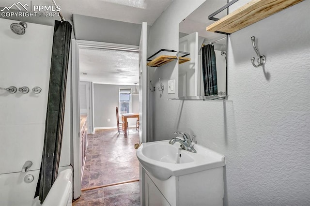 bathroom featuring a textured ceiling, vanity, and shower / bathtub combination with curtain