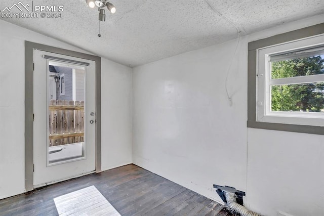 spare room featuring a textured ceiling, dark hardwood / wood-style flooring, and lofted ceiling