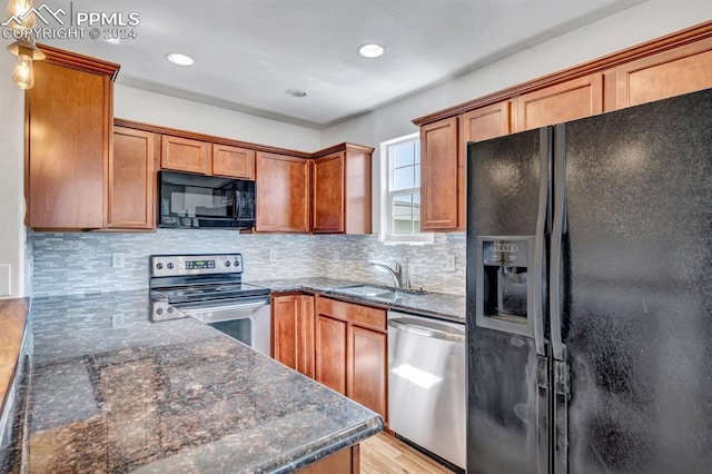 kitchen featuring black appliances, dark stone counters, decorative backsplash, sink, and light hardwood / wood-style flooring