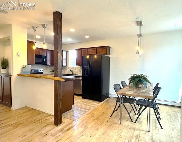 kitchen featuring black appliances, kitchen peninsula, light hardwood / wood-style floors, and pendant lighting