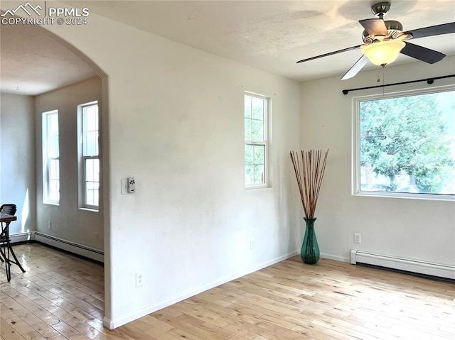 empty room with plenty of natural light, light hardwood / wood-style floors, and a baseboard radiator