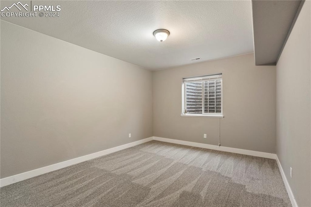 carpeted spare room with a textured ceiling