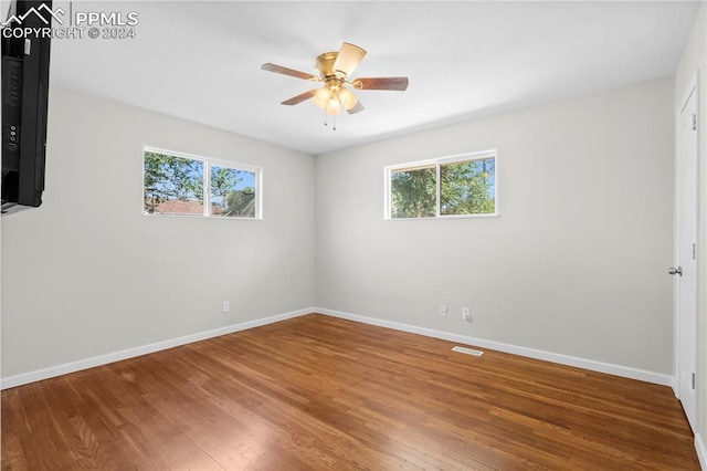 empty room with hardwood / wood-style flooring, ceiling fan, and a healthy amount of sunlight