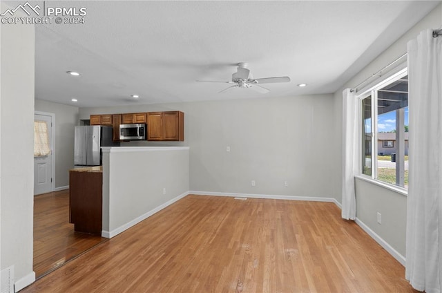 unfurnished living room featuring ceiling fan and light hardwood / wood-style flooring