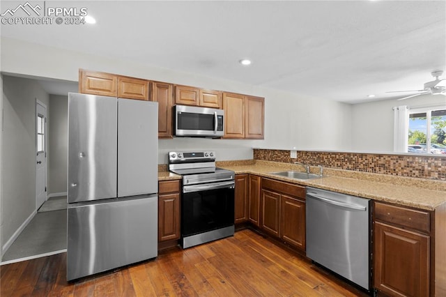 kitchen with sink, backsplash, ceiling fan, appliances with stainless steel finishes, and dark hardwood / wood-style floors