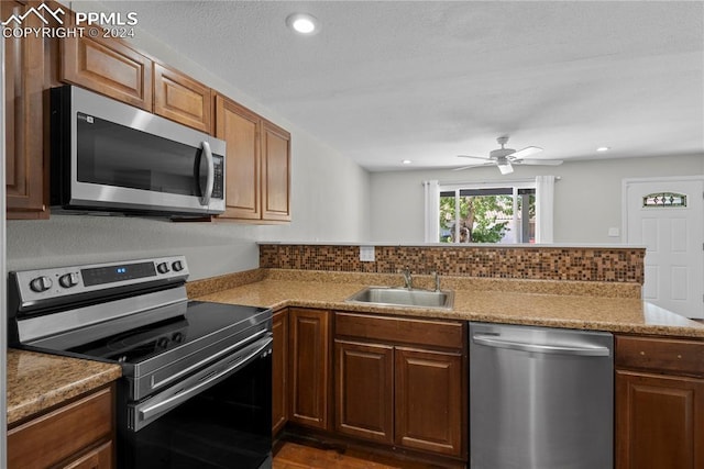 kitchen with kitchen peninsula, stainless steel appliances, sink, ceiling fan, and decorative backsplash