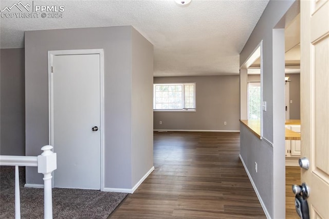 hall featuring a textured ceiling and dark hardwood / wood-style floors