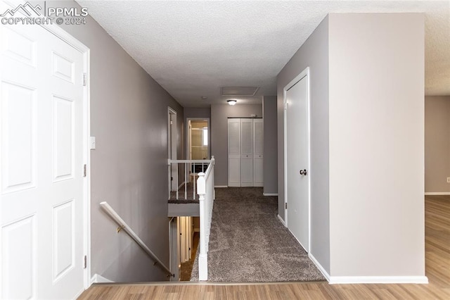 hall with a textured ceiling and light wood-type flooring