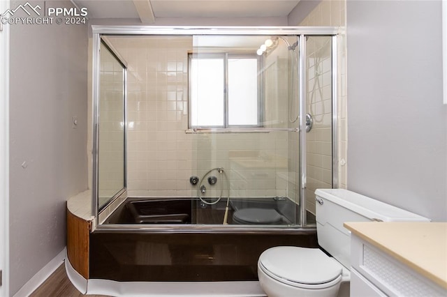 full bathroom with enclosed tub / shower combo, hardwood / wood-style floors, vanity, and toilet