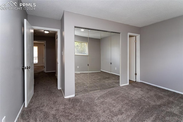 unfurnished bedroom with a closet, carpet flooring, a textured ceiling, and multiple windows