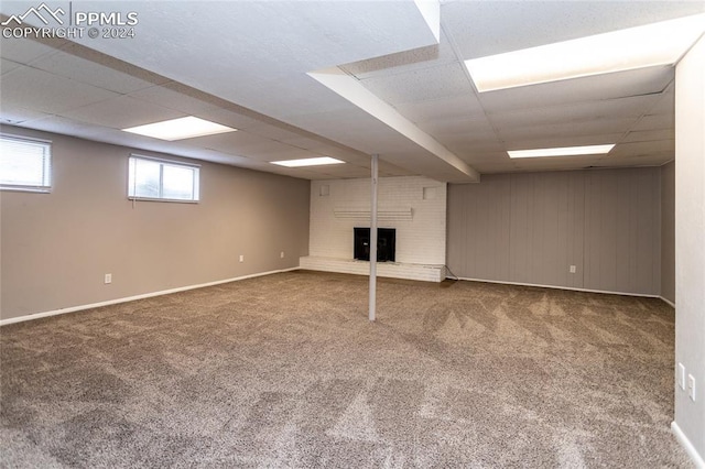 basement with carpet floors, a fireplace, and a drop ceiling