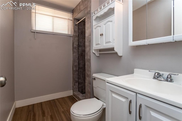 bathroom featuring tiled shower, hardwood / wood-style floors, vanity, and toilet