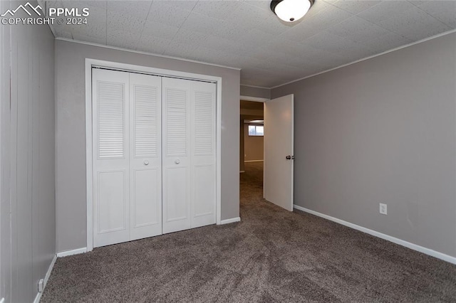 unfurnished bedroom featuring a closet and dark colored carpet