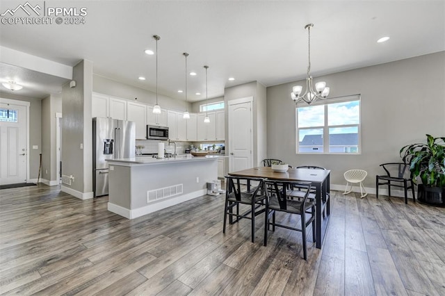 dining space with sink, hardwood / wood-style floors, a wealth of natural light, and an inviting chandelier