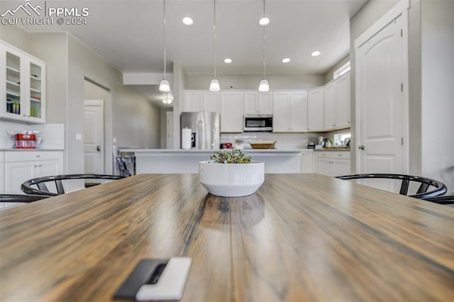 kitchen with appliances with stainless steel finishes, white cabinetry, and pendant lighting