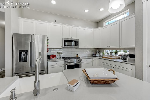 kitchen with tasteful backsplash, white cabinets, and high end appliances