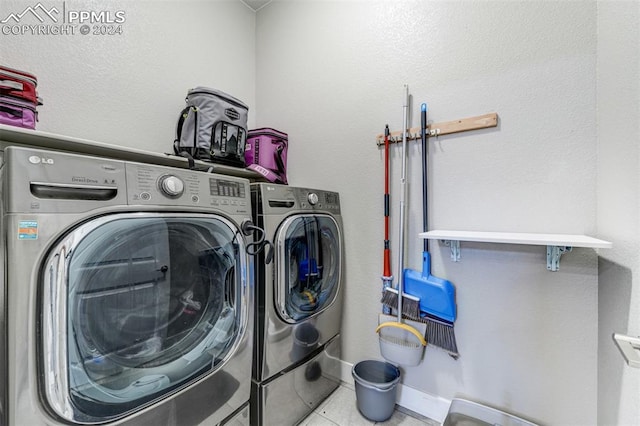 laundry area with washing machine and dryer and light tile patterned floors