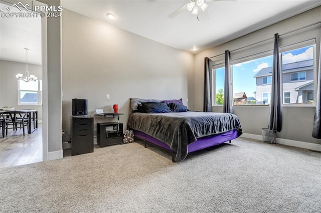 bedroom with hardwood / wood-style flooring and ceiling fan with notable chandelier