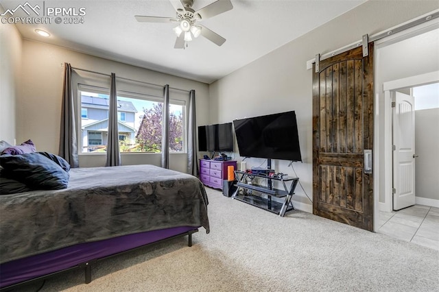 carpeted bedroom featuring a barn door and ceiling fan