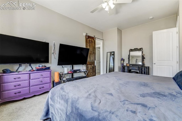 carpeted bedroom with a barn door and ceiling fan