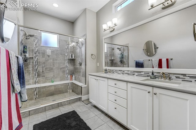 bathroom with decorative backsplash, tile patterned floors, a shower with shower door, and dual bowl vanity