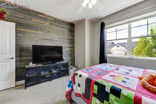 bedroom featuring wood walls, multiple windows, ceiling fan, and carpet floors