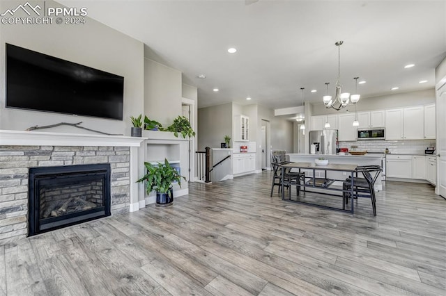 interior space featuring light hardwood / wood-style flooring, a stone fireplace, and a chandelier