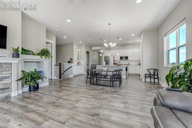 dining room featuring a fireplace, light hardwood / wood-style floors, and an inviting chandelier