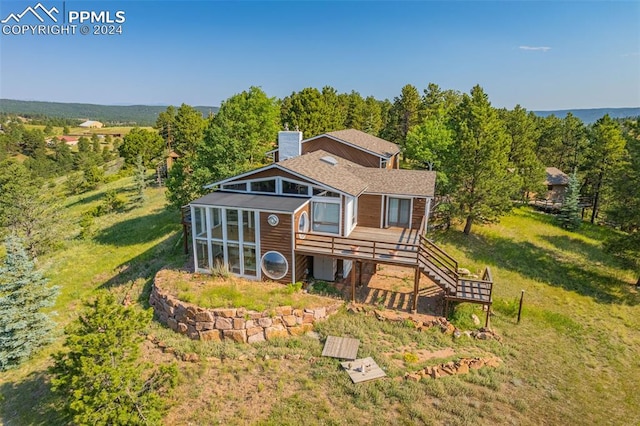 back of property featuring a wooden deck and a lawn