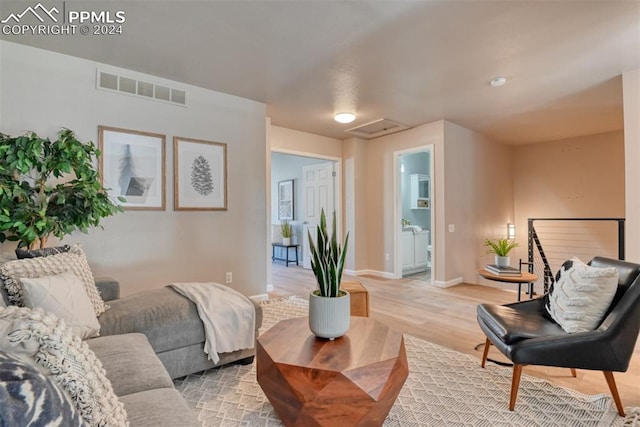 living room with washer and clothes dryer and light hardwood / wood-style flooring