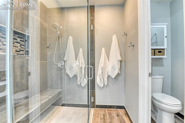 bathroom featuring a shower with door, hardwood / wood-style flooring, and toilet