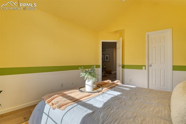 bedroom with wood-type flooring and vaulted ceiling