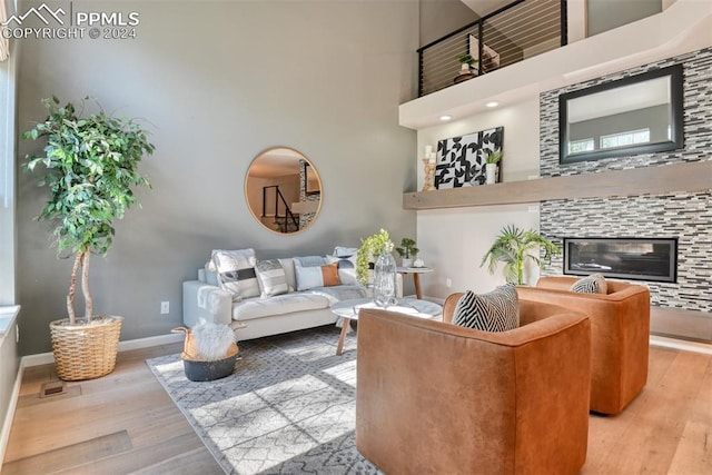 living room featuring a towering ceiling, a tile fireplace, and light hardwood / wood-style flooring