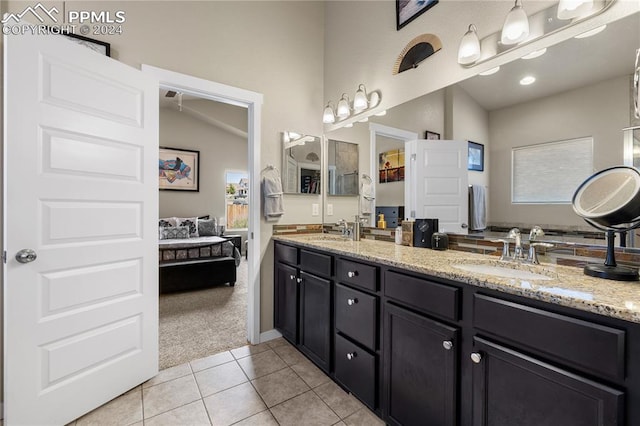 bathroom with dual vanity, tile patterned flooring, and vaulted ceiling