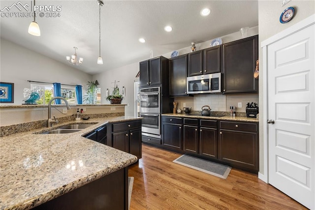 kitchen featuring light hardwood / wood-style floors, appliances with stainless steel finishes, pendant lighting, and vaulted ceiling