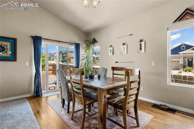 dining room with a notable chandelier, vaulted ceiling, light hardwood / wood-style flooring, and plenty of natural light